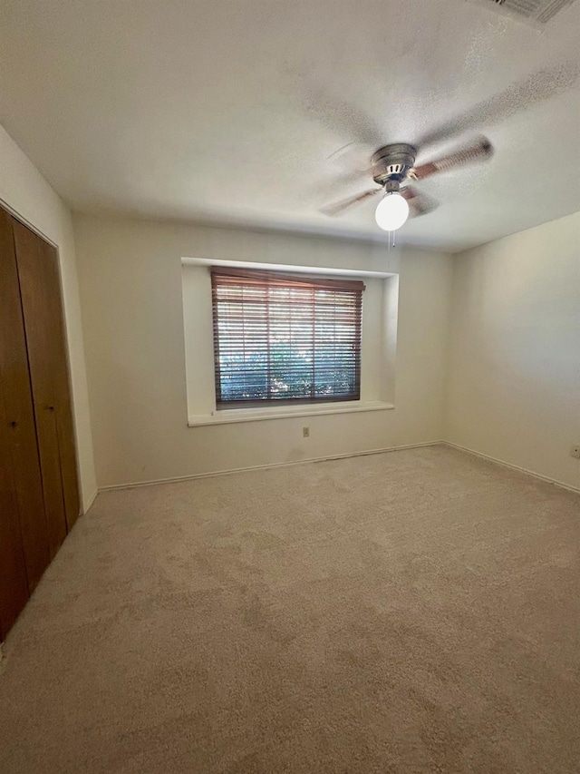 unfurnished bedroom featuring ceiling fan, a closet, a textured ceiling, and carpet