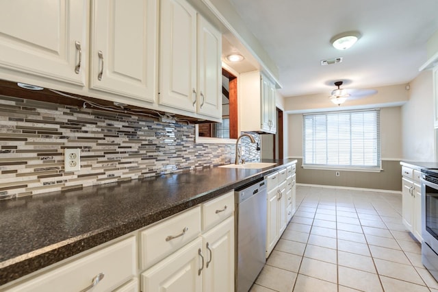 kitchen featuring sink, white cabinetry, light tile patterned floors, appliances with stainless steel finishes, and decorative backsplash