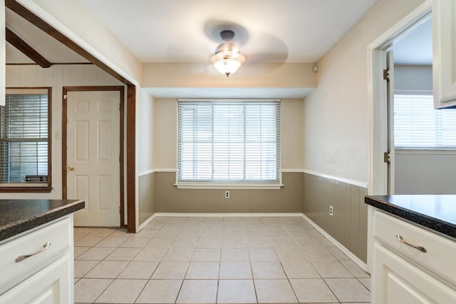 unfurnished dining area with light tile patterned floors and wood walls