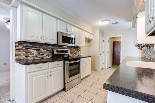 kitchen with appliances with stainless steel finishes, sink, white cabinets, backsplash, and light tile patterned floors