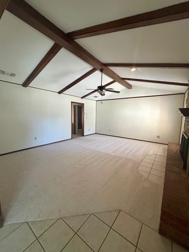 empty room with a fireplace, lofted ceiling with beams, ceiling fan, and carpet