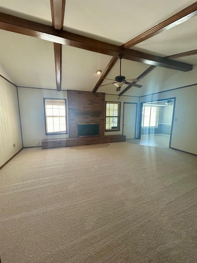 unfurnished living room with lofted ceiling with beams, ceiling fan, light carpet, and a fireplace