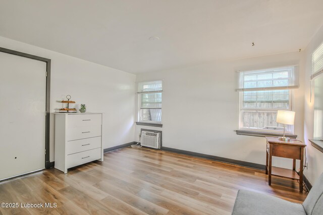 1901 31st St, Lubbock, TX 79411 - living area with healthy amount of natural light, wood finished floors, an AC wall unit, and baseboards