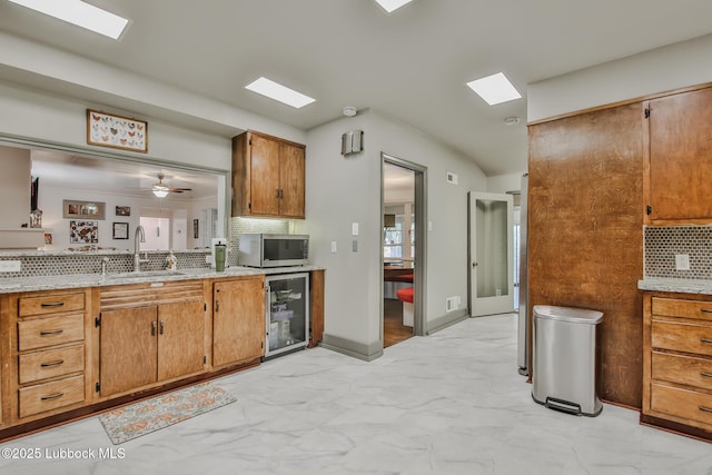 1901 31st St, Lubbock, TX 79411 - kitchen with wine cooler, stainless steel microwave, a sink, light marble finish floors, and decorative backsplash