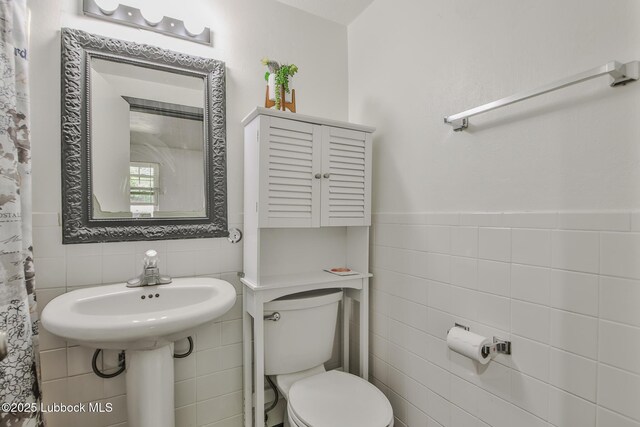 1901 31st St, Lubbock, TX 79411 - bathroom featuring tile walls, toilet, and wainscoting