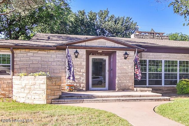1901 31st St, Lubbock, TX 79411 - view of exterior entry featuring stone siding and a shingled roof