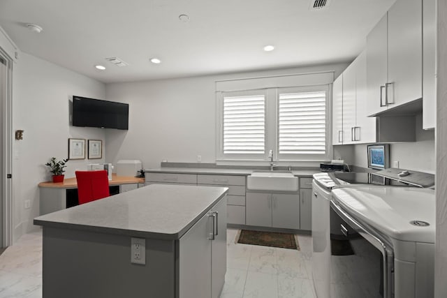 kitchen with marble finish floor, gray cabinets, a kitchen island, a sink, and independent washer and dryer