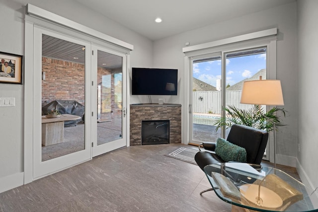 living area featuring a stone fireplace, recessed lighting, and baseboards