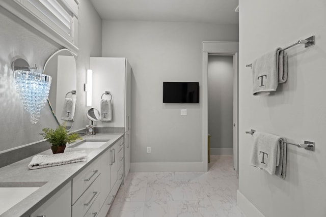 full bathroom featuring marble finish floor, double vanity, a sink, and baseboards