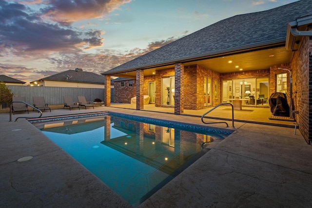 pool at dusk featuring a patio area, fence, and a fenced in pool