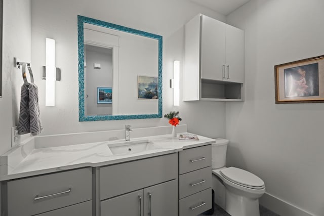 bathroom featuring baseboards, vanity, and toilet