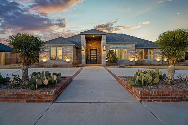 view of front facade with stone siding and fence