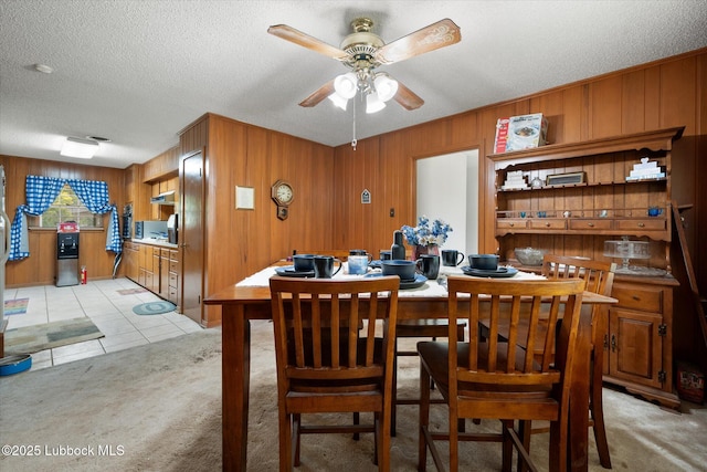 5426 28th St, Lubbock, TX 79407 - dining space with light colored carpet, a ceiling fan, wood walls, a textured ceiling, and light tile patterned flooring