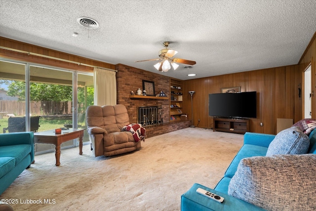 5426 28th St, Lubbock, TX 79407 - carpeted living room featuring wooden walls, ceiling fan, a fireplace, and a textured ceiling