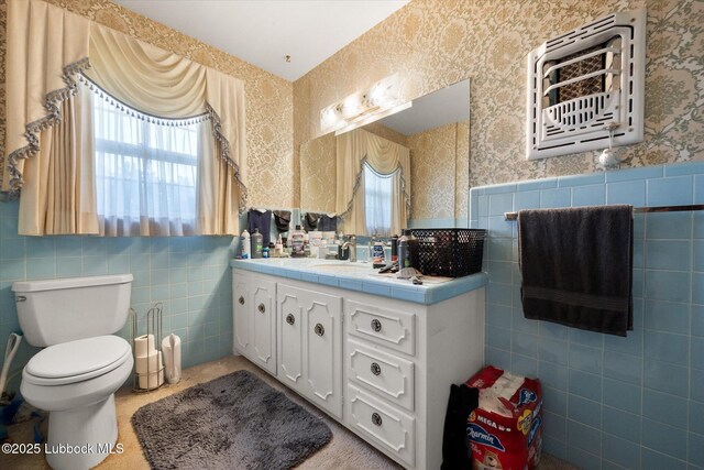 5426 28th St, Lubbock, TX 79407 - bathroom featuring tile walls, wallpapered walls, vanity, and wainscoting