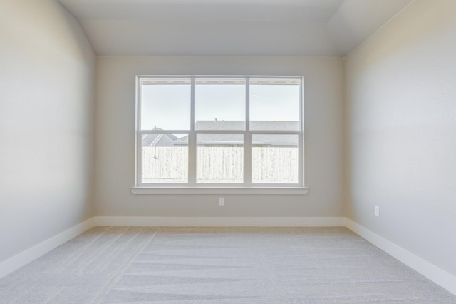 carpeted spare room featuring lofted ceiling