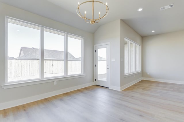 doorway with lofted ceiling, an inviting chandelier, and light hardwood / wood-style flooring