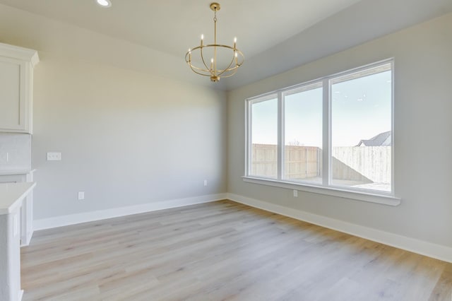 unfurnished dining area featuring plenty of natural light, a notable chandelier, and light hardwood / wood-style floors