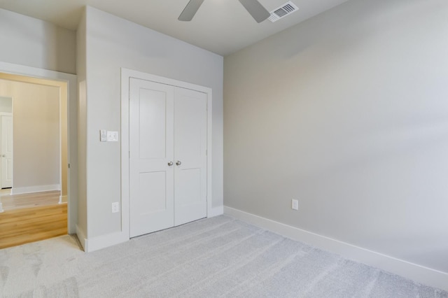 unfurnished bedroom with ceiling fan, light colored carpet, and a closet