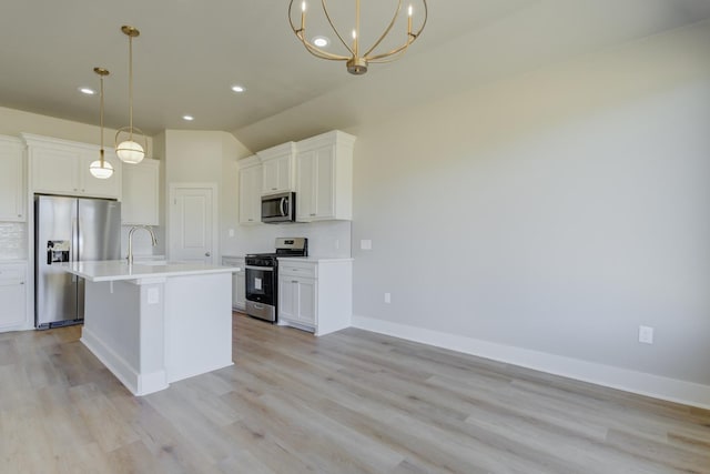 kitchen with stainless steel appliances, white cabinetry, hanging light fixtures, and a kitchen island with sink