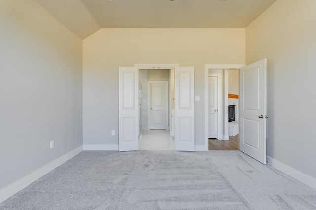 unfurnished bedroom featuring lofted ceiling and light carpet