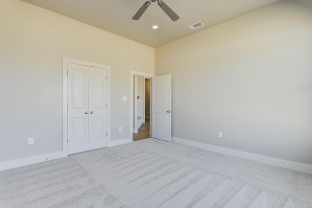 unfurnished bedroom featuring light carpet, a closet, and ceiling fan