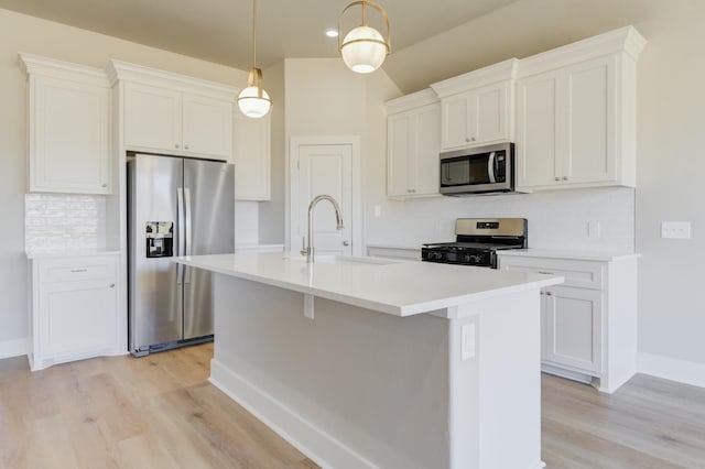 kitchen featuring pendant lighting, sink, appliances with stainless steel finishes, an island with sink, and white cabinets