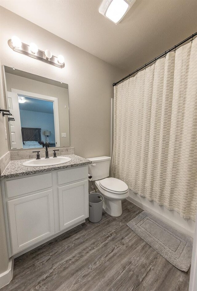 full bathroom with vanity, wood-type flooring, toilet, and shower / bath combo with shower curtain