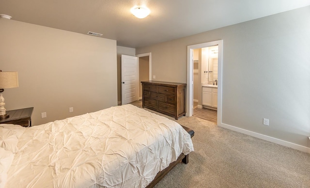 bedroom featuring ensuite bathroom and light colored carpet