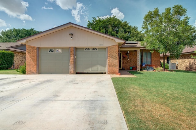 ranch-style house featuring a garage, cooling unit, a front lawn, and solar panels