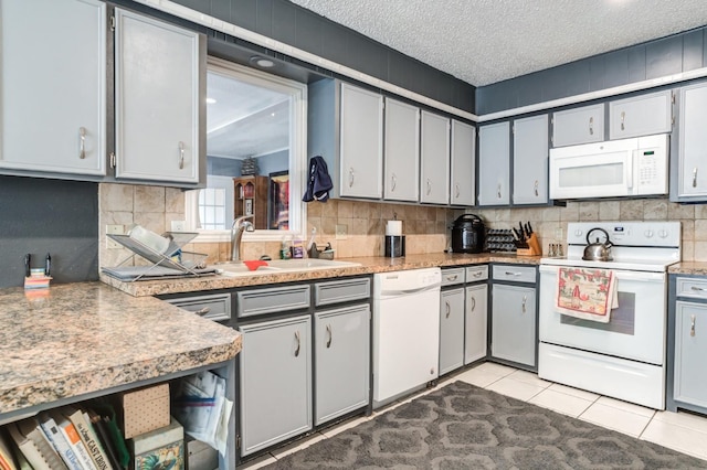 kitchen with gray cabinetry, a textured ceiling, and white appliances