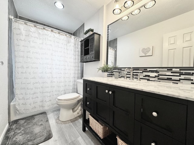 full bathroom featuring decorative backsplash, hardwood / wood-style flooring, vanity, toilet, and a textured ceiling