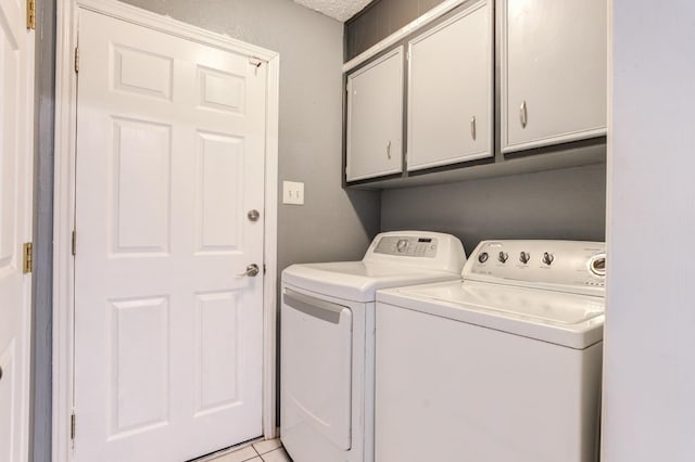 laundry area featuring light tile patterned flooring, cabinets, washer and clothes dryer, and a textured ceiling