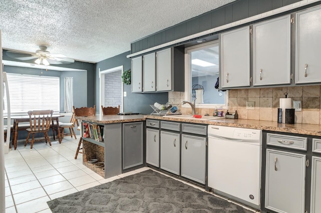 kitchen featuring dishwasher, sink, gray cabinetry, light tile patterned floors, and a textured ceiling