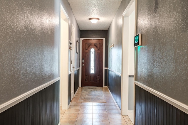 doorway with a textured ceiling and light tile patterned floors