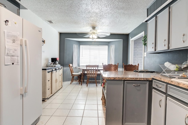 kitchen featuring light tile patterned floors, gray cabinets, ceiling fan, white refrigerator, and kitchen peninsula