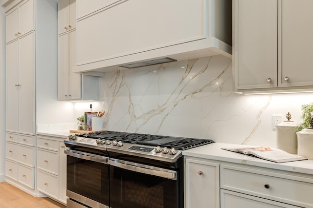 kitchen featuring range with two ovens, light stone countertops, and decorative backsplash