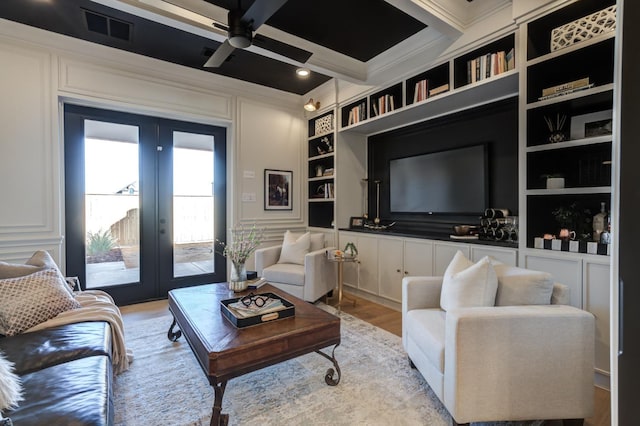 living room featuring french doors, coffered ceiling, crown molding, light hardwood / wood-style flooring, and built in features