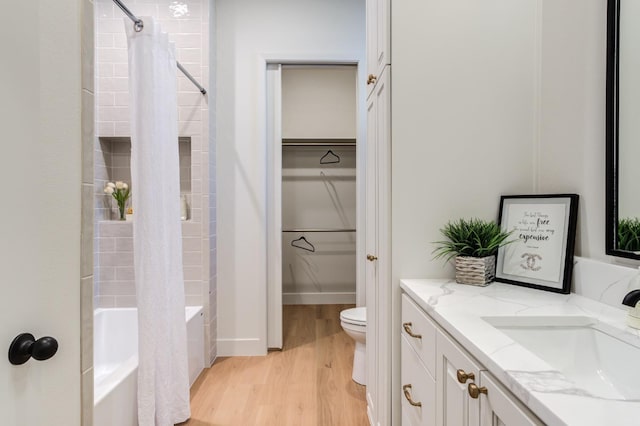 full bathroom featuring hardwood / wood-style flooring, vanity, shower / tub combo with curtain, and toilet