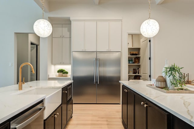 kitchen with dark brown cabinetry, hanging light fixtures, white cabinets, and appliances with stainless steel finishes