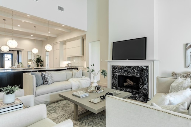 living room with a towering ceiling, a fireplace, and beam ceiling