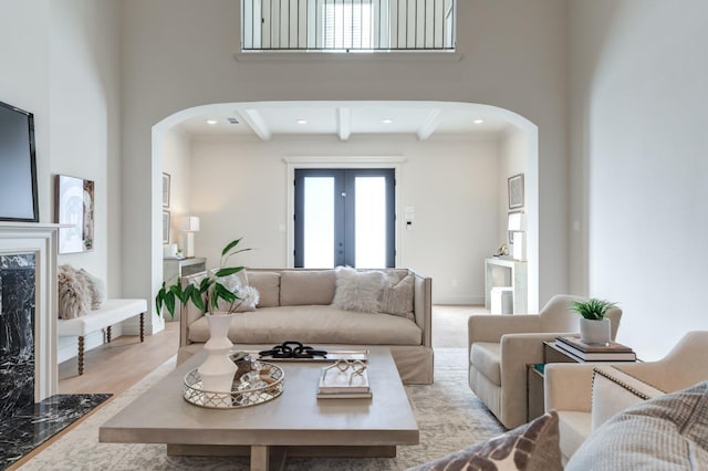 living room featuring beamed ceiling, a high ceiling, and french doors