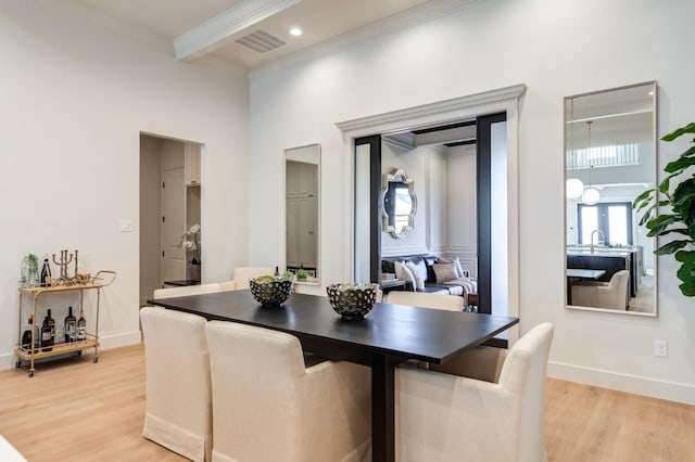 dining room with a high ceiling, ornamental molding, and light wood-type flooring