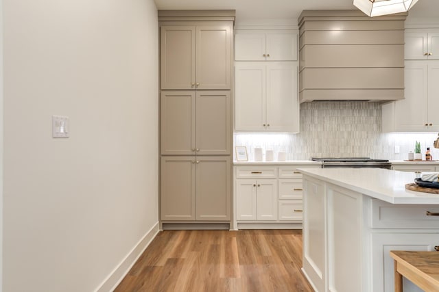 4610 138th Pl, Lubbock, TX 79424 - kitchen featuring custom exhaust hood, light countertops, light wood finished floors, decorative backsplash, and a kitchen breakfast bar