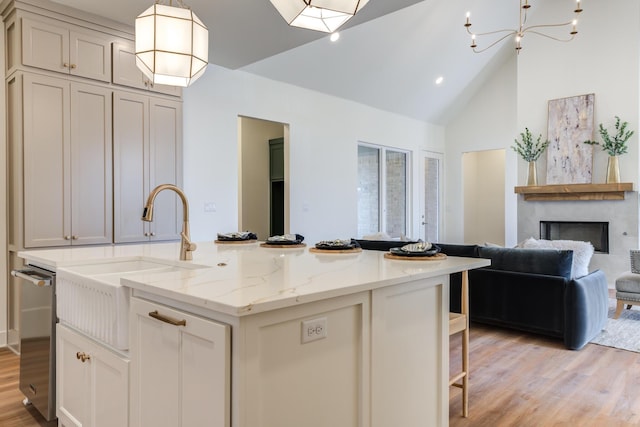 4610 138th Pl, Lubbock, TX 79424 - kitchen featuring light wood-type flooring, open floor plan, high vaulted ceiling, light stone counters, and a center island with sink