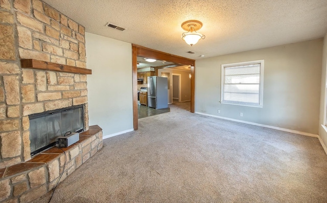 unfurnished living room with dark colored carpet, a textured ceiling, and a fireplace