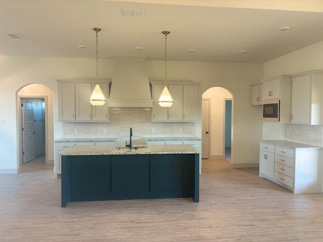 kitchen with tasteful backsplash, pendant lighting, custom exhaust hood, and black microwave