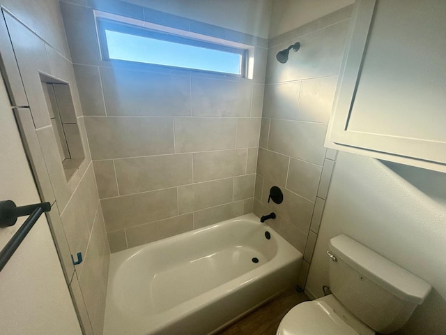 bathroom featuring tiled shower / bath combo and toilet