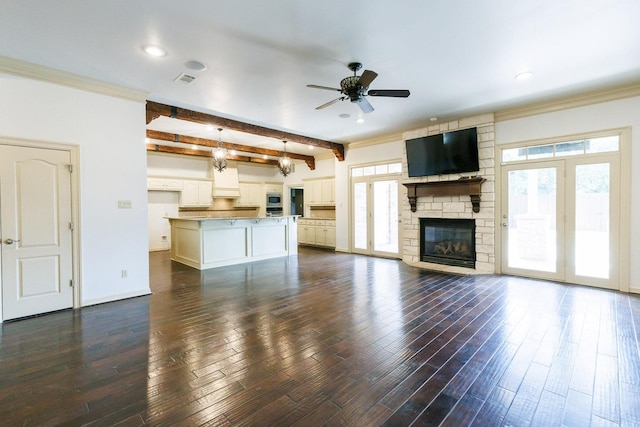 unfurnished living room with dark wood-type flooring, ceiling fan, beam ceiling, and a wealth of natural light