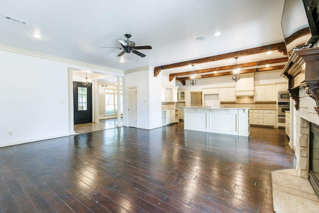 unfurnished living room featuring beamed ceiling, a fireplace, ceiling fan with notable chandelier, and dark wood-type flooring